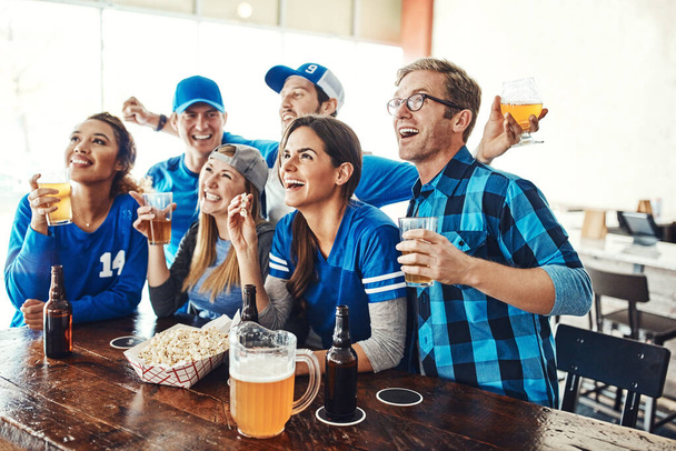 Avec qui mieux vaut regarder le match que les copains. un groupe d'amis buvant des bières en regardant un match de sport dans un bar - Photo, image