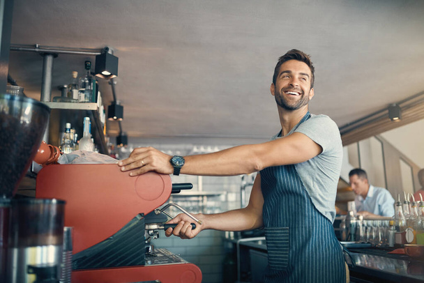 O ingrediente secreto é a paixão. um jovem operando a máquina de café em um café - Foto, Imagem