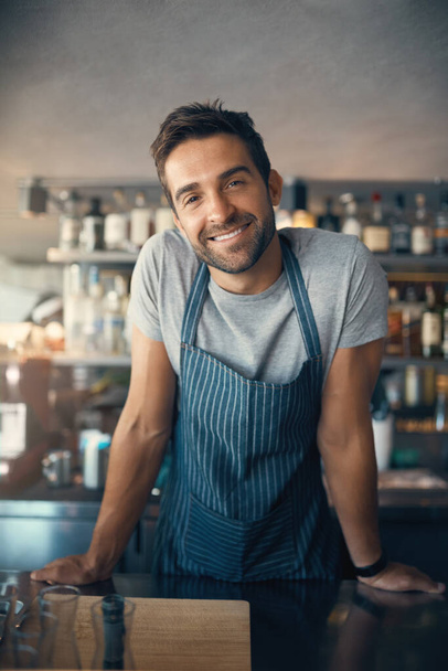 How can I make your coffee dreams come true. Portrait of a young man working behind a bar counter - Foto, Imagen