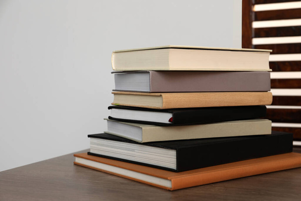 Stack of different hardcover books on wooden table indoors. Space for text - Fotografie, Obrázek