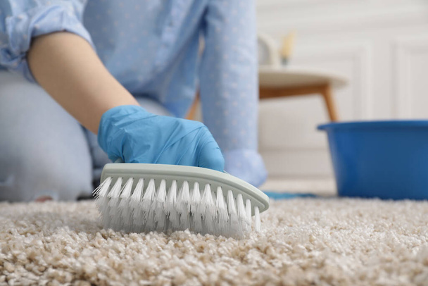 Woman in rubber gloves cleaning carpet with brush indoors, closeup. Space for text - Фото, зображення