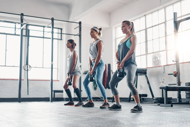 Ez a gyakorlat minden jó helyen működik. Három nő edz súlyzóval az edzőteremben. - Fotó, kép