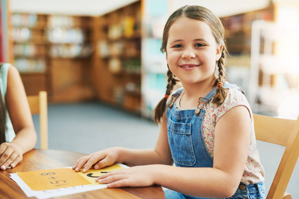 Estou pronto para aprender. Retrato de uma menina alegre fazendo seu trabalho escolar enquanto estava sentada em uma sala de aula dentro durante o dia - Foto, Imagem