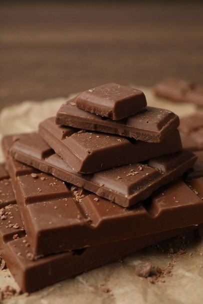 Pieces and crumbs of tasty chocolate bars on table, closeup - 写真・画像