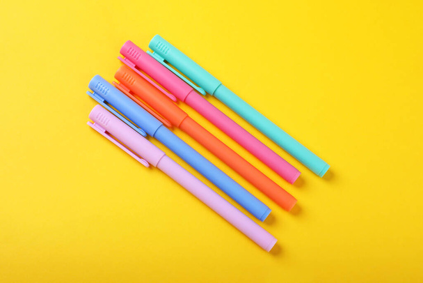 Many colorful markers on yellow background, flat lay - Foto, Imagen