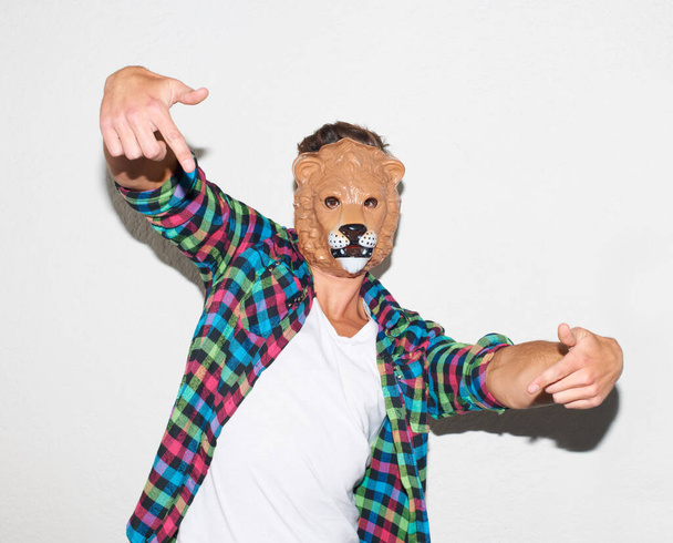 Animal mask, hand gesture and a man in studio with cool attitude to party with a positive mindset. Lion face or male model person isolated on a white background for fun, funny and goofy portrait. - Foto, Imagen