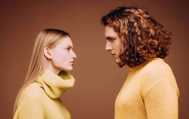 Side view. Curly man and blonde woman facing each other, eyes open. Concept of confrontation in the family. A couple standing face to face with a piercing look. Boyfriend and girlfriend hating each - Photo, image