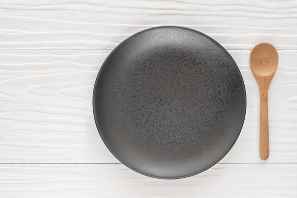Czarne miski ceramiczne i drewnianą łyżką na biały drewniany stół - Zdjęcie, obraz
