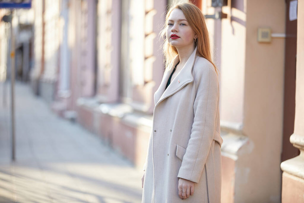 fashion woman in coat with red lips posing on the street  - Фото, изображение