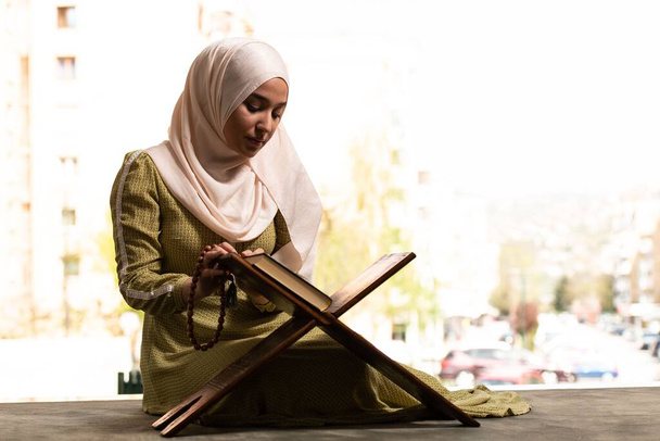 A Beautiful Muslim Woman in Hijab Dress Sitting in Mosque and Praying With Quran - Zdjęcie, obraz