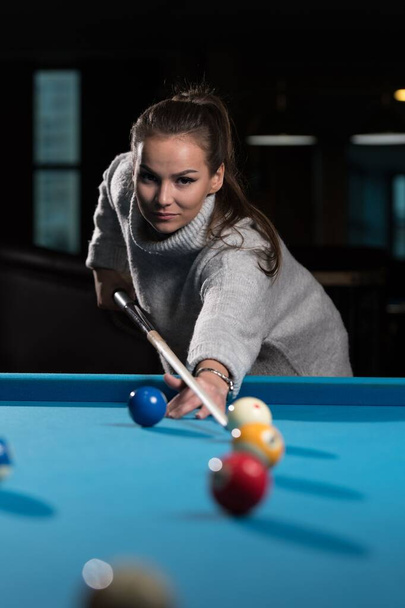 A vertical closeup of a young woman playing billiards. - Foto, imagen