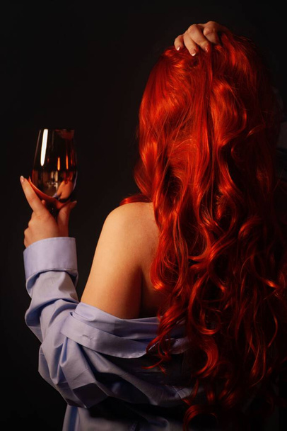 Elegant woman with a glass of wine is waiting in a hotel room for her romance. - Φωτογραφία, εικόνα