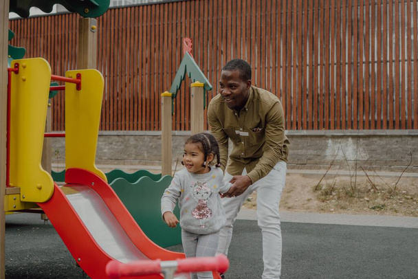 A happy little girl with her dad in a playground - Photo, Image