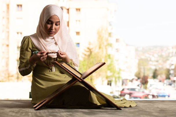 A Beautiful Muslim Woman in Hijab Dress Sitting in Mosque and Praying With Quran - Фото, зображення