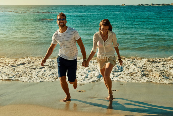 Its not summer until you get your feet wet. a happy young couple running along the beach - Φωτογραφία, εικόνα