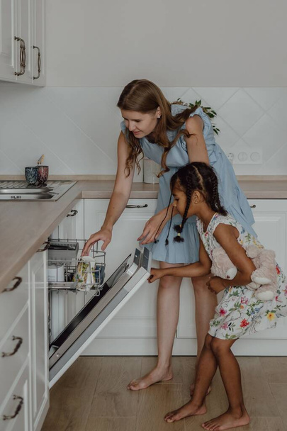 The Hispanic mother and daughter using the dishwasher in the kitchen - Fotografie, Obrázek