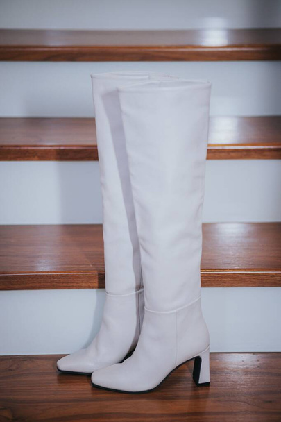 A vertical shot of white boots on a wooden stairs - Photo, Image