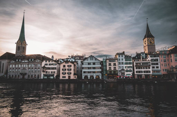 Das Ufer der Limmat mit der Kirche St. Peter und Fraumünster bei Sonnenuntergang in Zürich, Schweiz - Foto, Bild