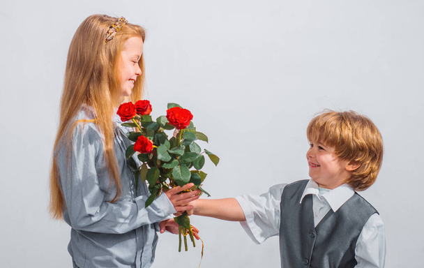 Niño pequeño con una rosa para su novia adolescente, niños románticos, aislado sobre fondo blanco. Concepto de amor - Foto, Imagen