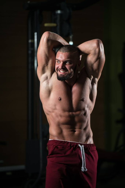 Een verticaal portret van een aantrekkelijk fitnessmodel van zijn atletische lichaam na een workout - Foto, afbeelding