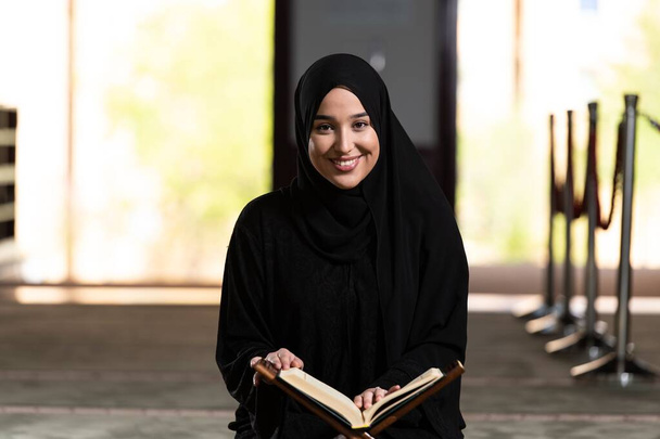A beautiful Muslim woman in a mosque reading Quran. Muslim faith, culture. - Fotó, kép
