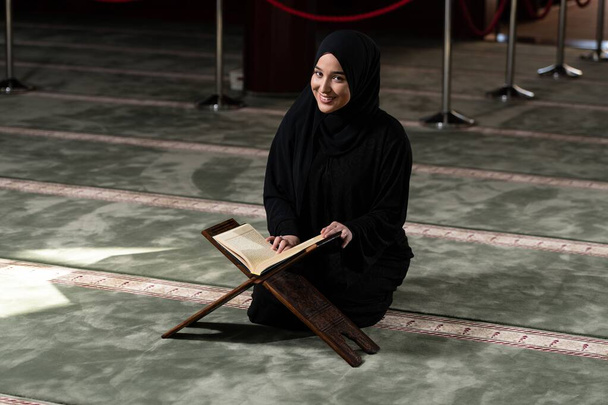 A beautiful Muslim woman in a mosque reading Quran. Muslim faith, culture. - Foto, Imagem