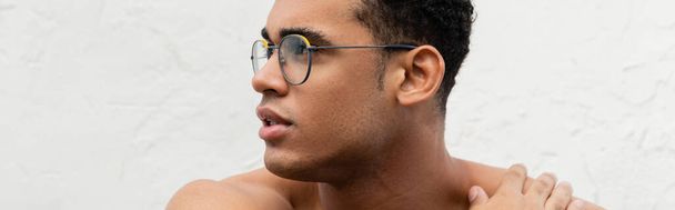 Portret van een Cubaanse man zonder shirt in stijlvolle ronde brillen die de schouder raken, spandoek  - Foto, afbeelding
