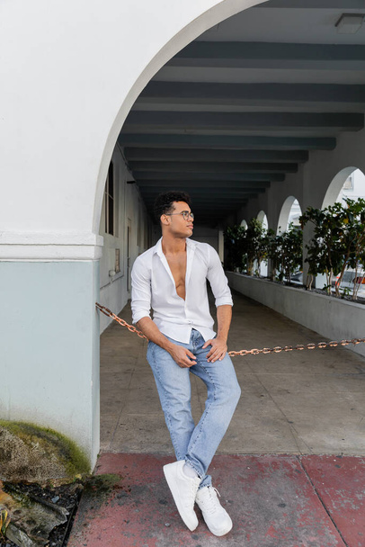 Full length of stylish νεαρός Κουβανός με πουκάμισο και στυλάτα στρογγυλά γυαλιά στο Μαϊάμι - Φωτογραφία, εικόνα