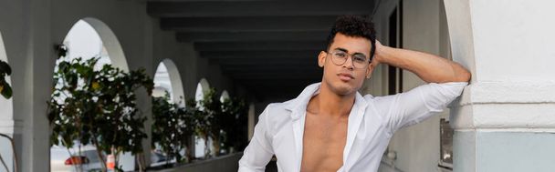 Sexy joven cubano con gafas elegantes y camisa blanca mirando a la cámara en Miami, pancarta - Foto, imagen