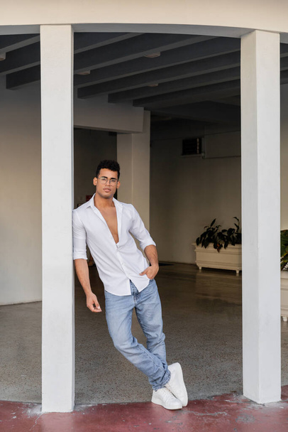 Plná délka stylového kubánského muže v kulatých brýlích, bílé košili a džínách stojící v Miami - Fotografie, Obrázek