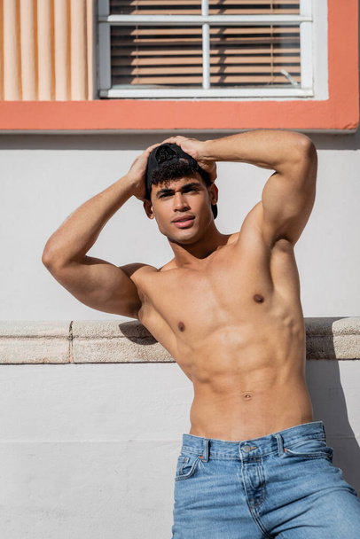 shirtless cuban man with sexy body in baseball cap and jeans standing on street in Miami - Photo, Image