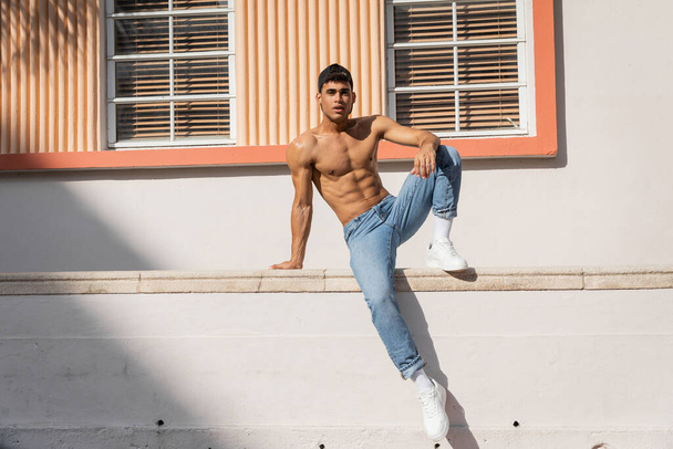Kubánský muž s svalnatým tělem pózující v baseballové čepici a džínách na ulici v Miami v létě - Fotografie, Obrázek
