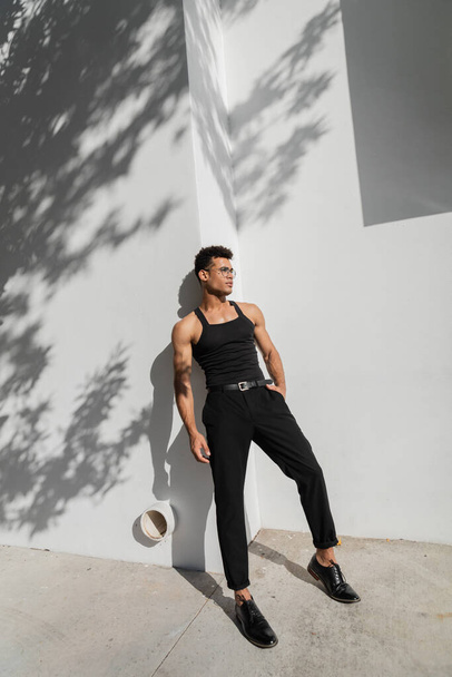 sexy junger kubanischer Mann posiert in der Nähe einer weißen Mauer mit Schatten auf einer städtischen Straße in Miami, Südstrand - Foto, Bild
