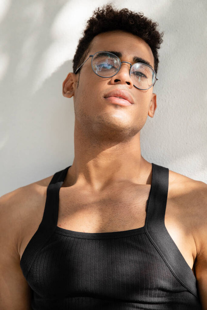 Muotokuva trendikäs ja lihaksikas kuubalainen mies silmälasit ja hihaton t-paita katselee kameraa  - Valokuva, kuva