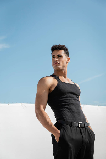 muscular young cuban man in black sleeveless t-shirt and pants posing in Miami, south beach - Foto, Imagen