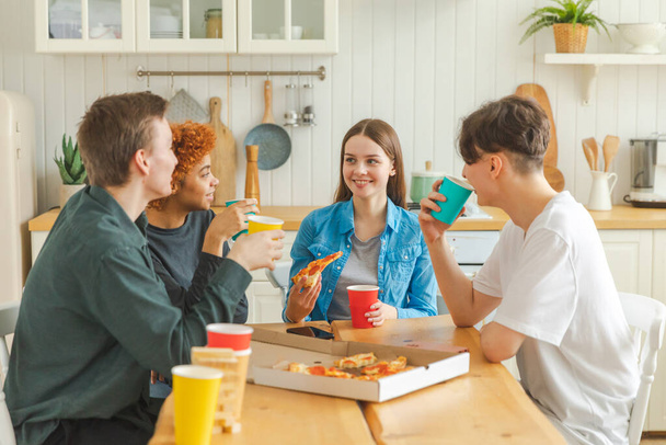 Kotibileet. Ystävät viettävät aikaa yhdessä hauskaa nauraa kommunikoida kotona. Onnellinen monipuolinen ryhmä syö pizzaa juomalla olutta tai limonadia. Sekarotuinen nuori kaverit parhaita ystäviä nauttia viikonloppuna - Valokuva, kuva
