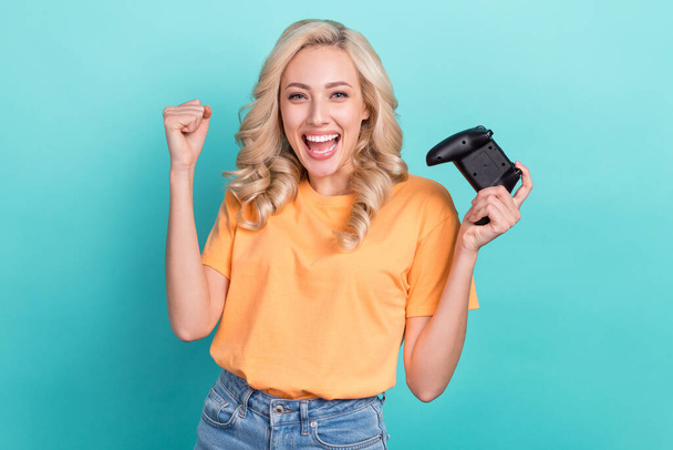 Photo of lucky excited lady dressed orange t-shirt rising fist winning playstation game isolated teal color background. - Φωτογραφία, εικόνα