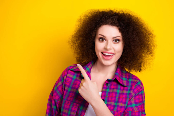 Photo of young funny excited girl unexpected reaction indicates fingers empty space open new interesting facts isolated on yellow color background. - Foto, Imagen