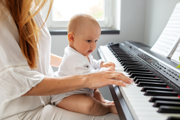 Mother and baby daughter playing piano. Baby development. Sensory experience. Brain development. Early years. - Photo, Image