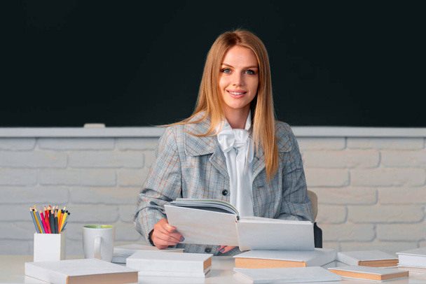 Female student on lesson lecture in classroom at high school or college. Smiling student reading book on blackboard background with copy space - Foto, Imagem
