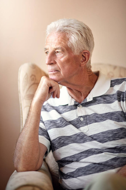 Is it too late. a senior man sitting on a chair and looking thoughtful at home - Foto, afbeelding