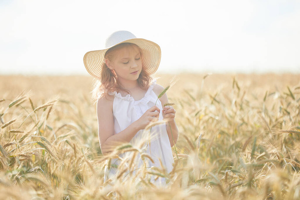 Portrait of happy girl in hat standing in wheat field  - Photo, image