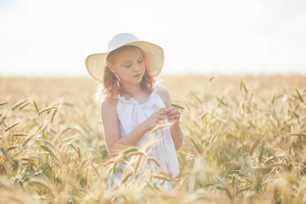 Portrait of happy girl in hat standing in wheat field  - Foto, afbeelding