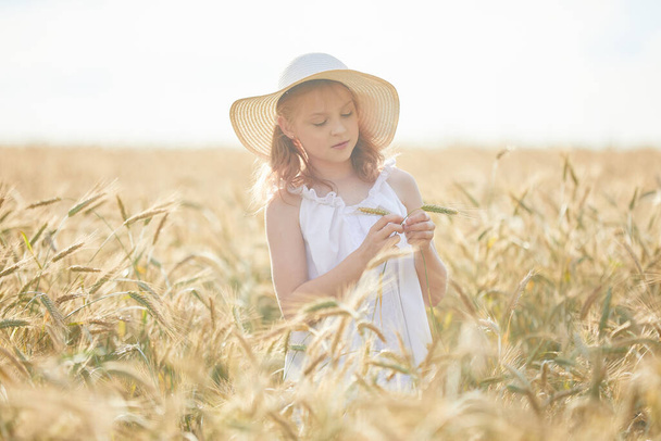 Portrait of happy girl in hat standing in wheat field  - Foto, Imagen