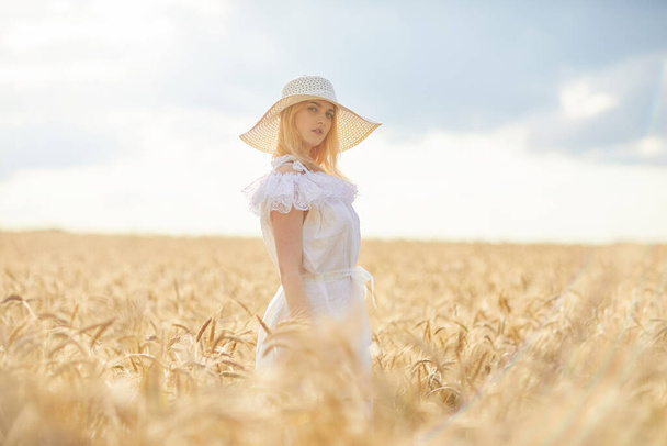 caucasian woman in hat, posing in wheat field during daytime - Фото, изображение