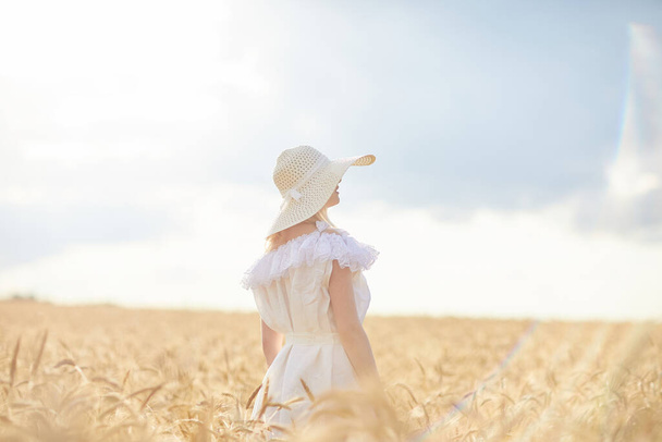 caucasian woman in hat posing in wheat field during daytime - Foto, afbeelding
