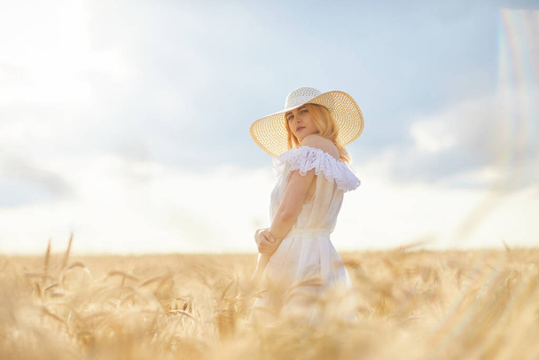 белая женщина в шляпе, позирующая на пшеничном поле днем - Фото, изображение
