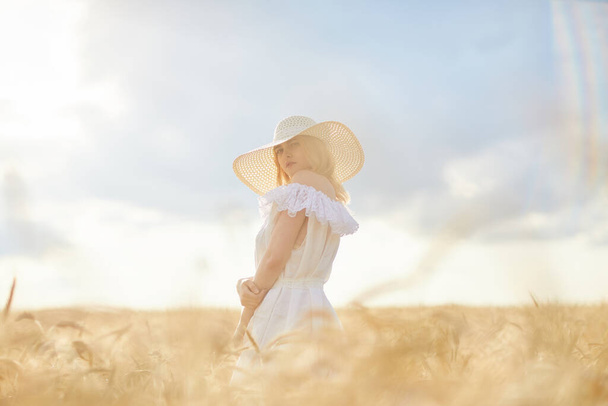 caucasian woman in hat posing in wheat field during daytime - Фото, изображение