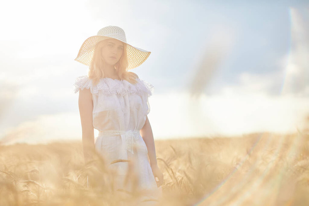 caucasian woman in hat posing in wheat field during daytime - Фото, изображение
