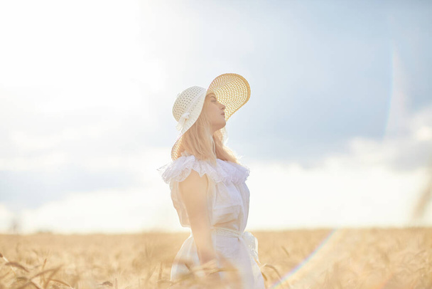 caucasian woman in hat posing in wheat field during daytime - Φωτογραφία, εικόνα